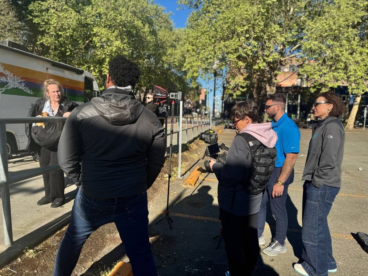 A team filming a patient's story beside a mobile clinic