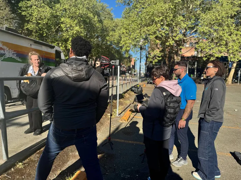 A team filming a patient's story beside a mobile clinic